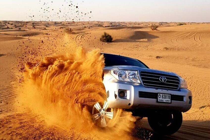 Un SUV blanco circulando por un desierto, levantando arena con los neumáticos. 2