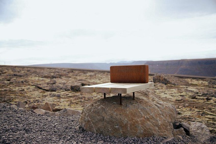 A wooden bench on a rock with a barren landscape in the background. 3
