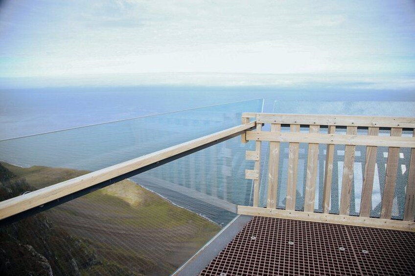 A wooden railing overlooking a coastal area with a view of the sea and distant land. 4