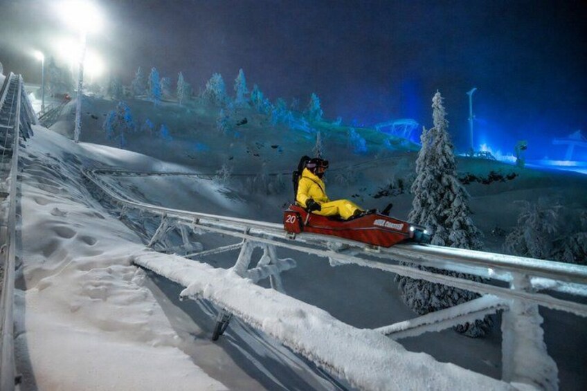 A person sledding down a snowy slope at night. 1