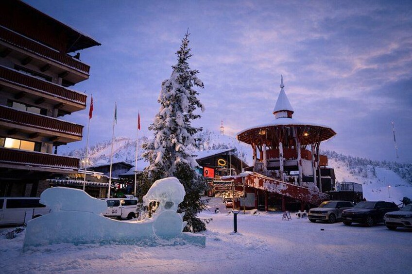 A snow-covered ski resort with a lodge, a large snow sculpture, and a mountain in the background. 4