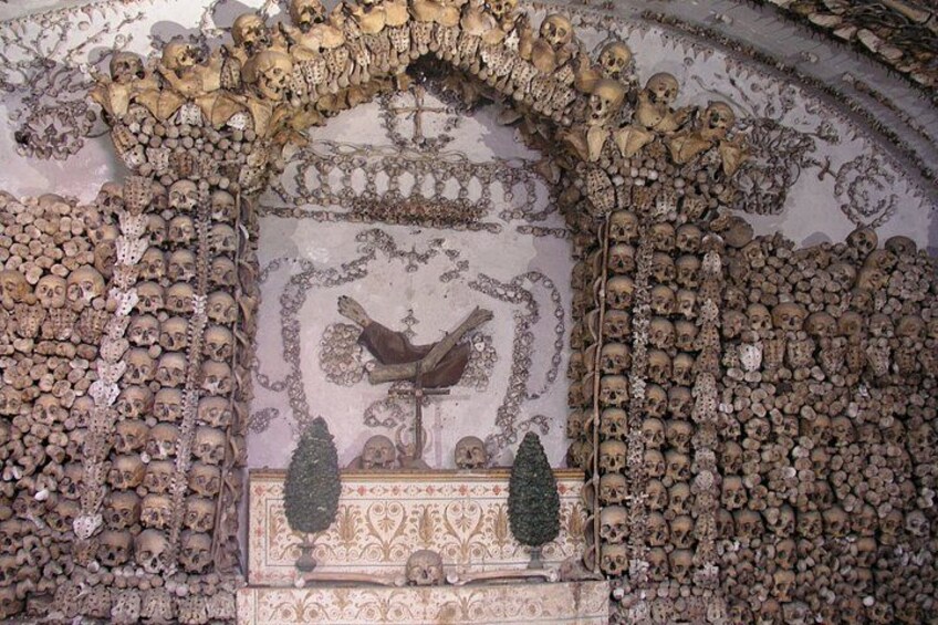 Un mausoleo con cráneos dispuestos en complejos diseños y un sarcófago central. 3