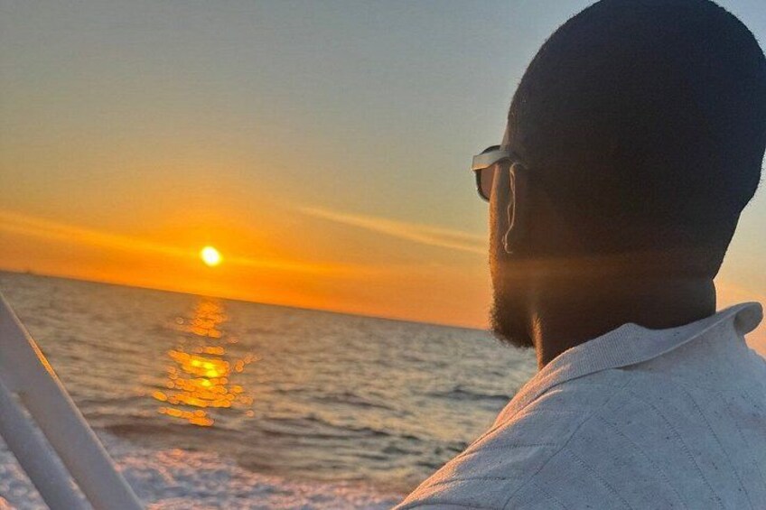 A person facing the sunset over the ocean. 5