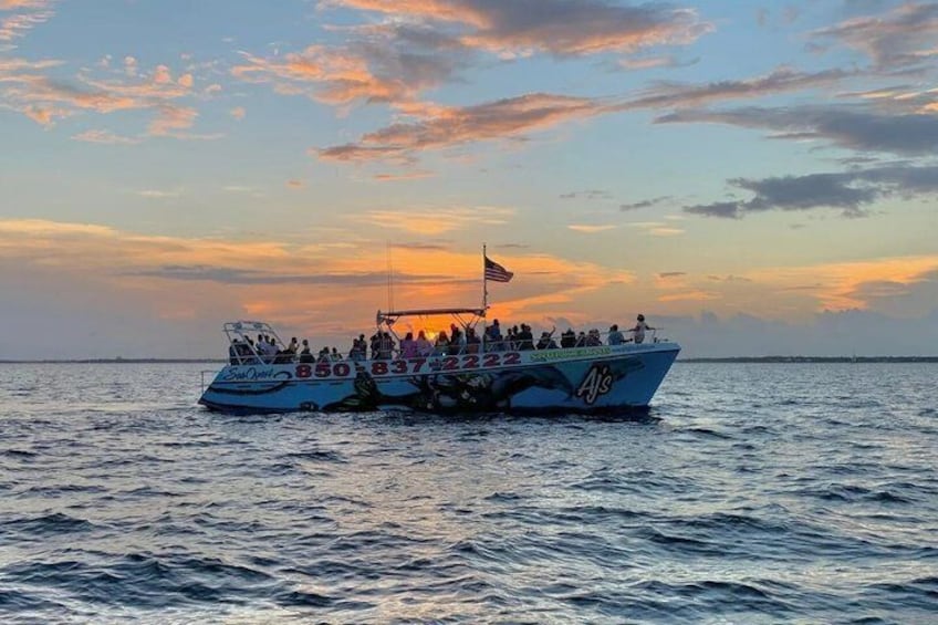 A boat with multiple passengers on a calm sea during sunset. 1