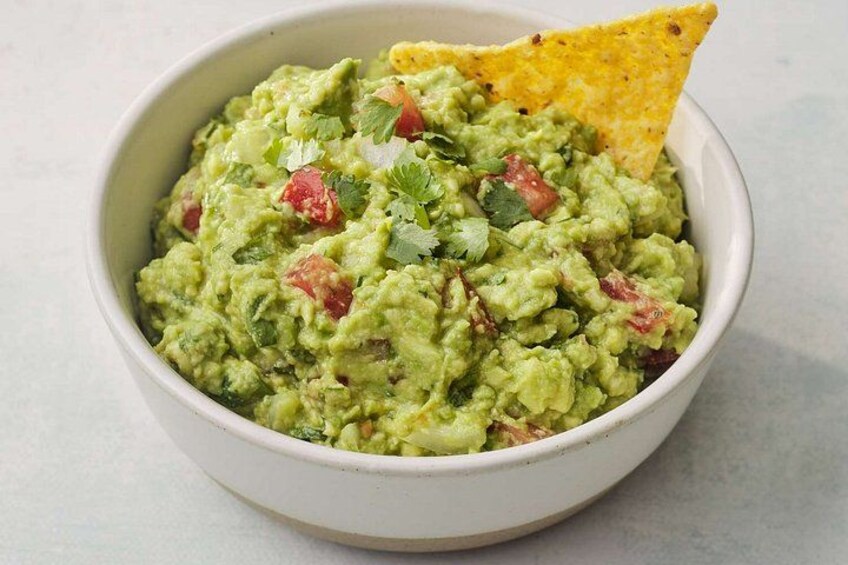 A bowl of guacamole with a tortilla chip. 3