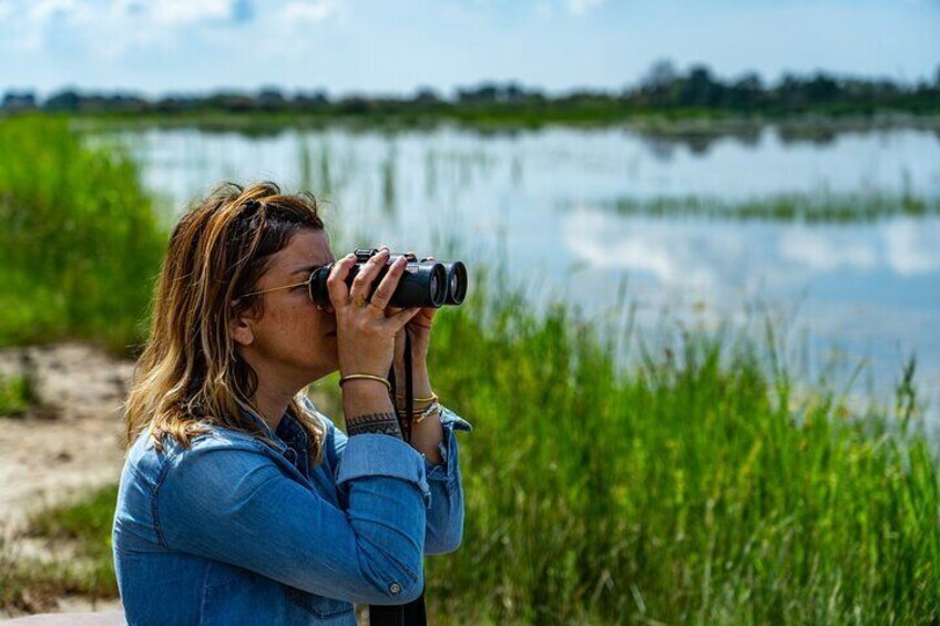 A person taking a photograph with a camera near a body of water and greenery. 4