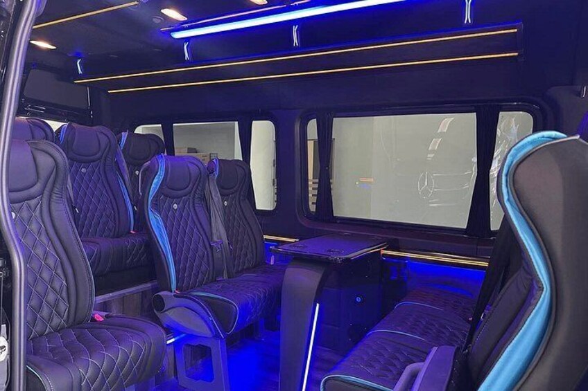 Een voertuiginterieur met leren stoelen, blauwe lichtaccenten en een middenconsole. 4