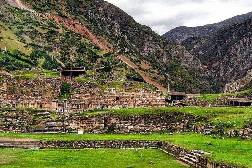Ancient ruins with stone structures and steps, set against a mountainous backdrop. 5