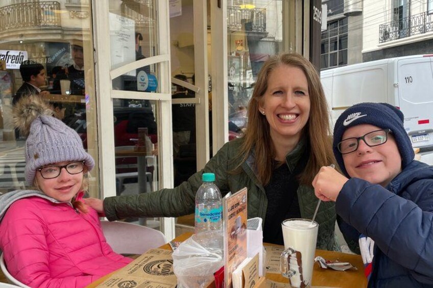 Drie personen zitten aan een tafel met een drankje en een waterfles. 5