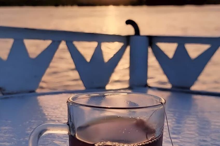 A glass mug on a white bench with a metal railing in the background. 3