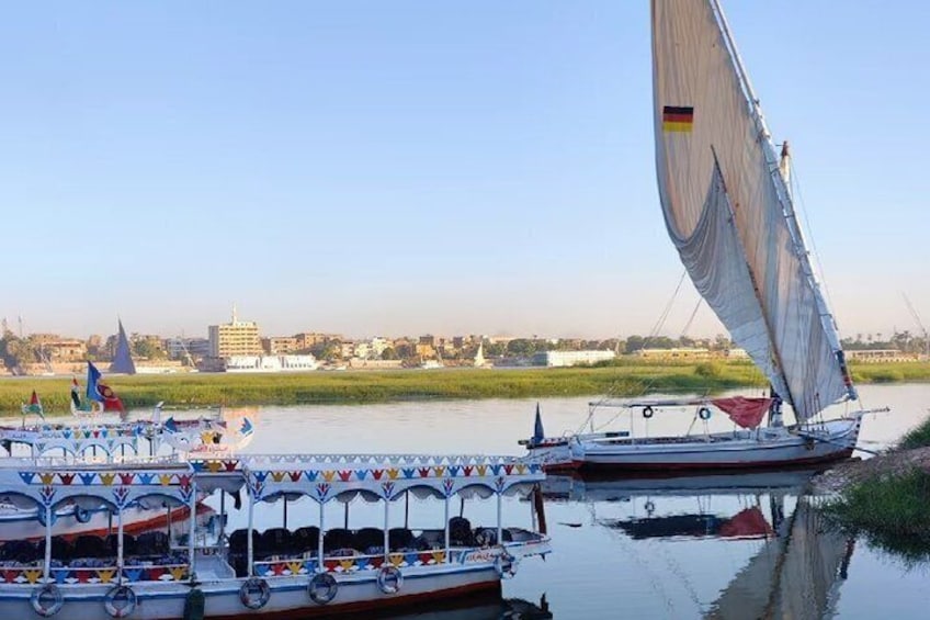 A river with boats, including a sailboat with a German flag, and a cityscape in the background. 5