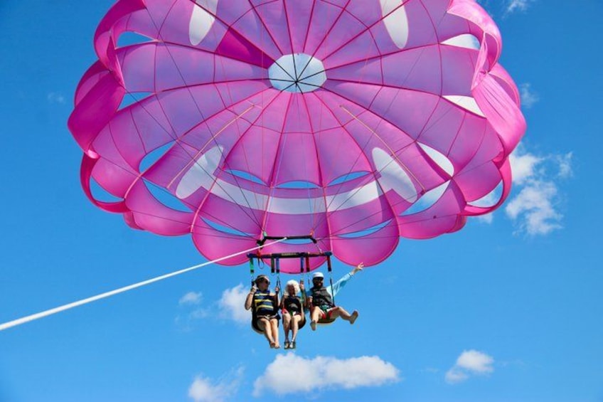 A person parachuting with a large pink parachute against a clear blue sky. 1