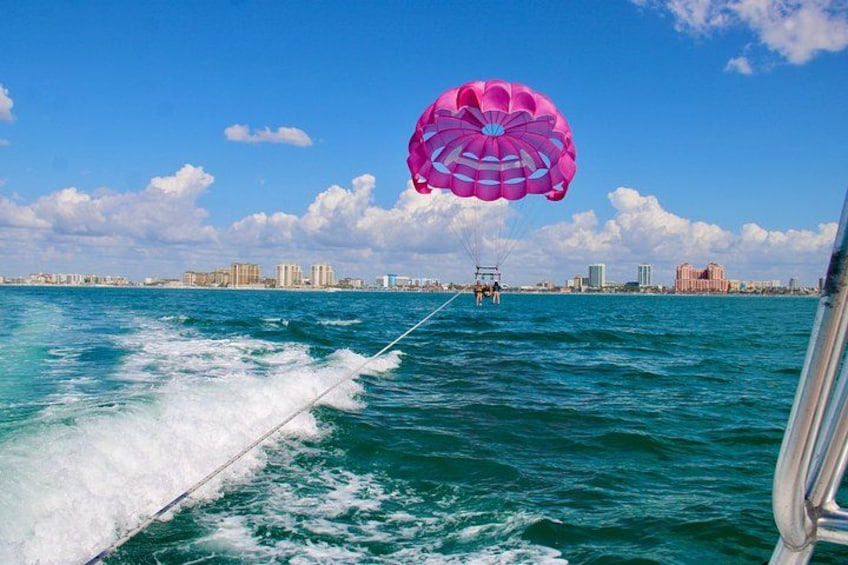 A parasailing activity over turquoise water with a city skyline in the background. 2