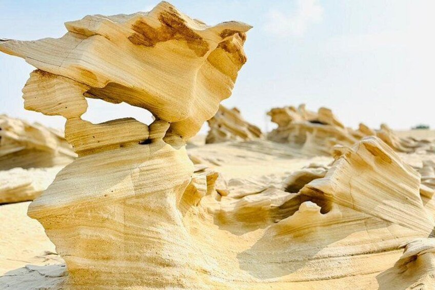 Un gros plan d’une formation rocheuse naturelle aux textures superposées, avec un ciel dégagé en arrière-plan. 1
