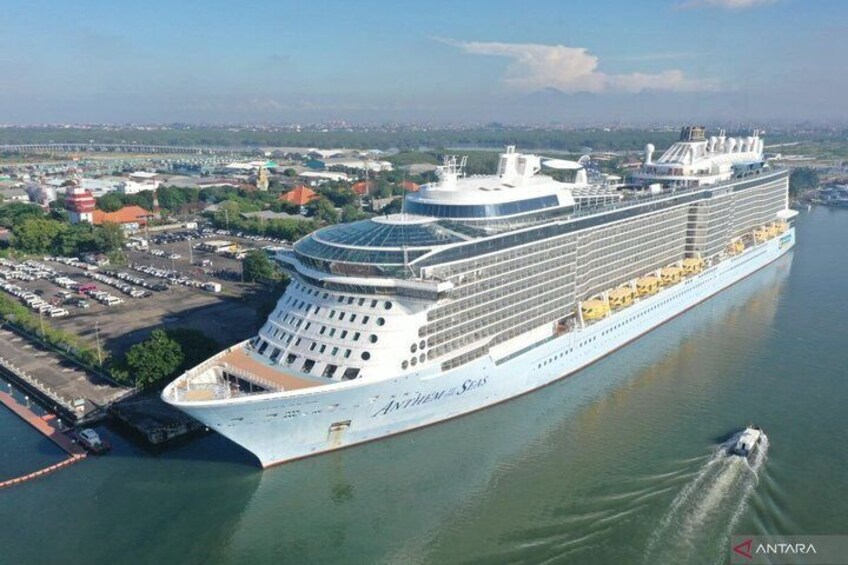 Un gran crucero llamado 'ANTARA' atracado en un puerto con un paisaje urbano de fondo. 1