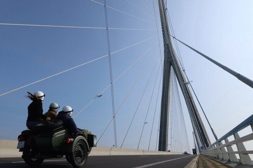 Una motocicleta con dos pasajeros cruzando un puente. 3