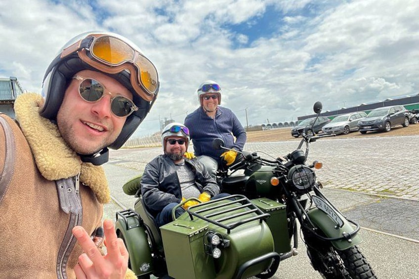 Tre personer på en motorcykel med ladcykel, belagt vej og en overskyet himmel. 2