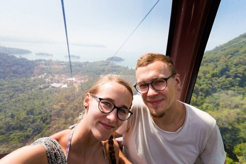 Two people on a cable car with a mountainous landscape in the background. 1