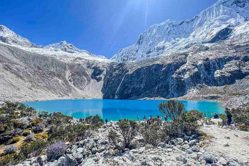 A turquoise lake surrounded by rocky mountains and sparse vegetation. 2