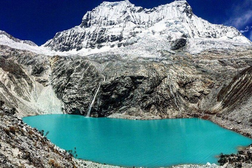 A turquoise lake surrounded by rugged mountains and a snow-capped peak. 1