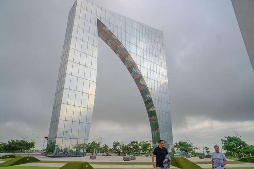 A tall glass building with a curved facade, surrounded by a park with green lawns and trees. 2