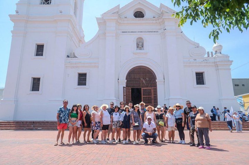 A group of people standing in front of a white colonial-style building with a large arched doorway. 5