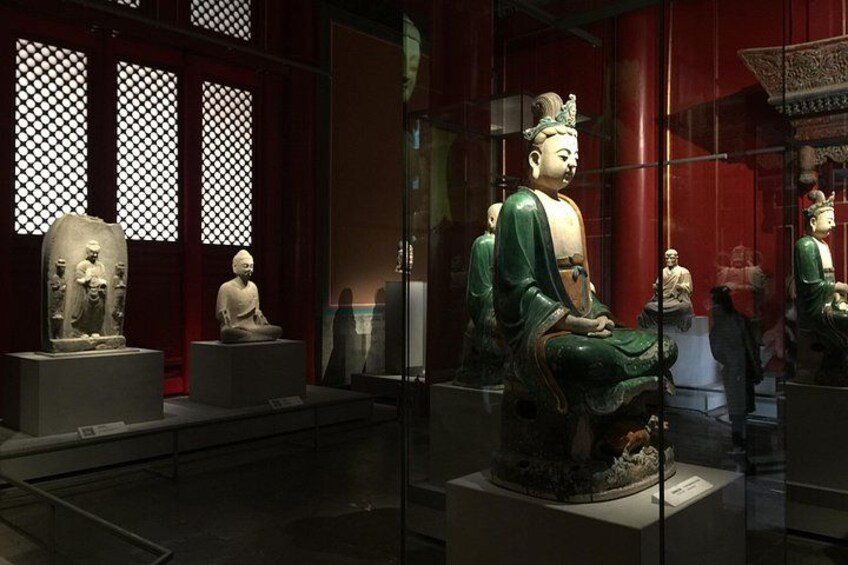A museum exhibit with statues of Buddha in various poses, displayed on pedestals. 4