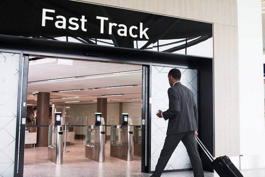 A man in a suit walking through a glass door labeled 'Fast Track' with a suitcase. 2