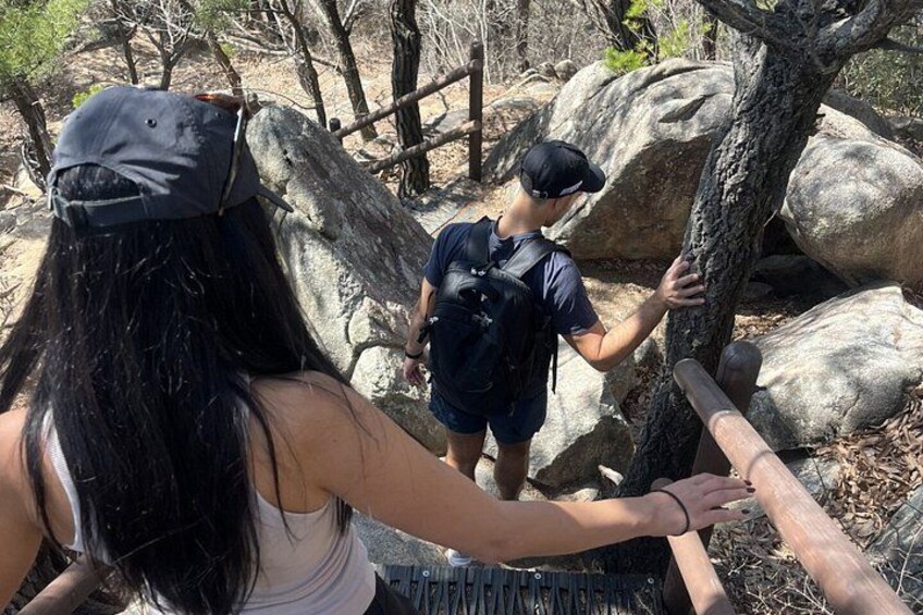 Two people hiking near a rocky trail with large boulders. 3