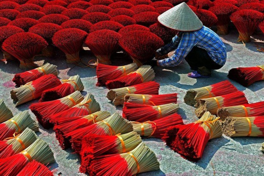A person arranging red flowers and bundles of red and yellow materials on the ground. 3