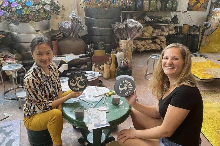 Two people holding ceramic pieces in a workshop with pottery tools and materials. 4