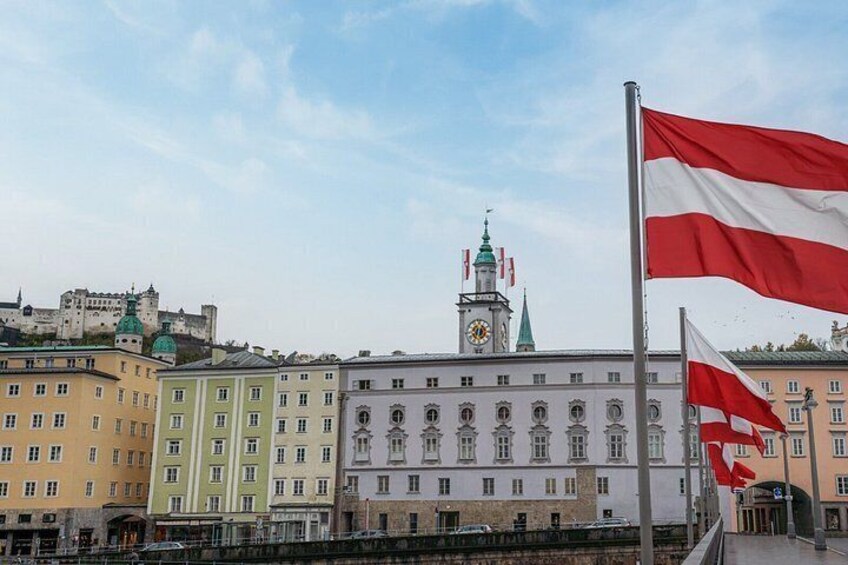 A historic building with a clock tower, a flag, and a river in the foreground. 4