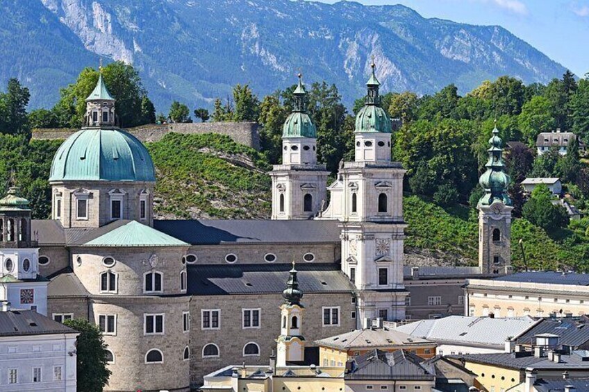 A historic building with domed roofs and a mountainous backdrop. 5