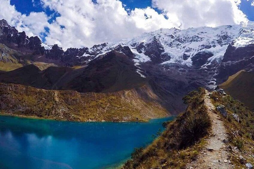 A mountain landscape with a turquoise lake, snow-capped peaks, and a narrow path. 5