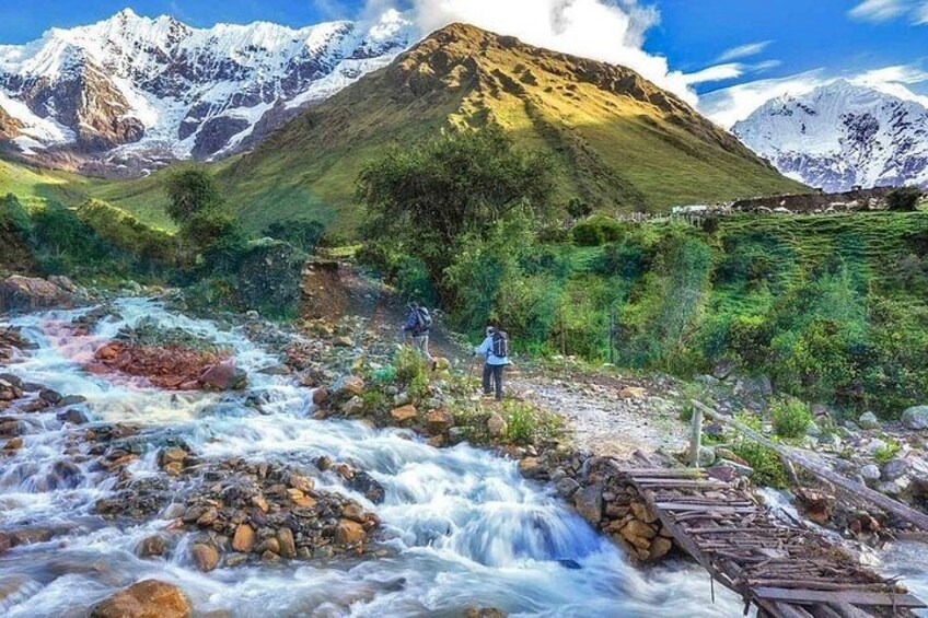 A river flowing through a mountainous landscape with a person standing on a bridge. 1