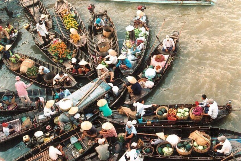 A group of canoes filled with people and produce on a river. 2