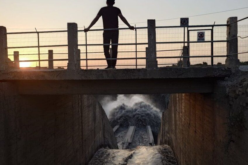 Une personne se tient sur un pont muni d’une barrière, d’où elle contemple une cascade. 5