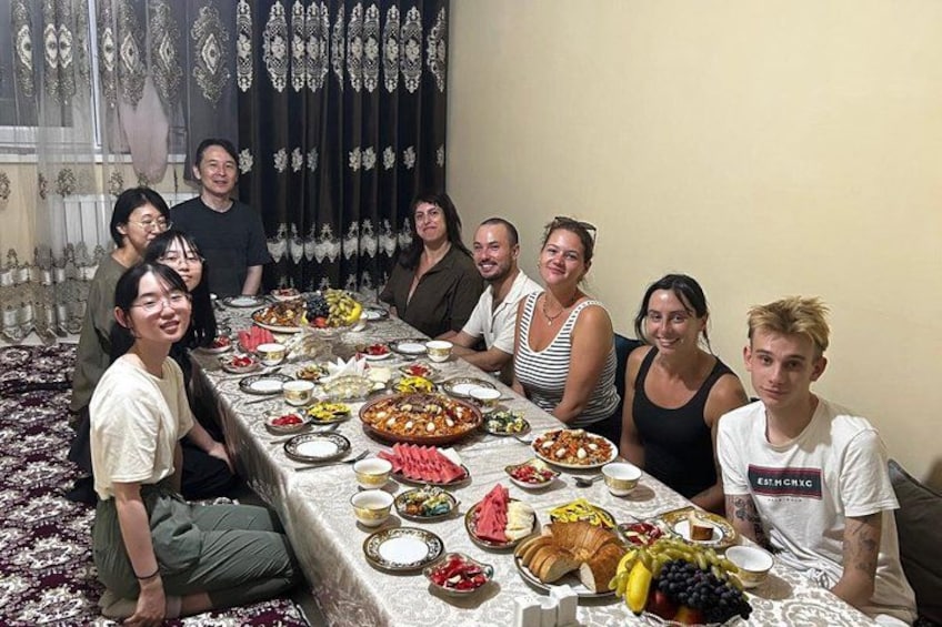 Un groupe de personnes est assis autour d’une table, devant divers plats et des fruits. 4