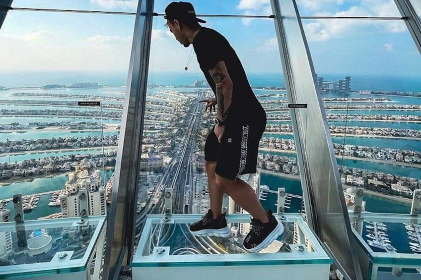 Une personne se tient sur un plancher de verre, avec une vue sur le paysage urbain. 1