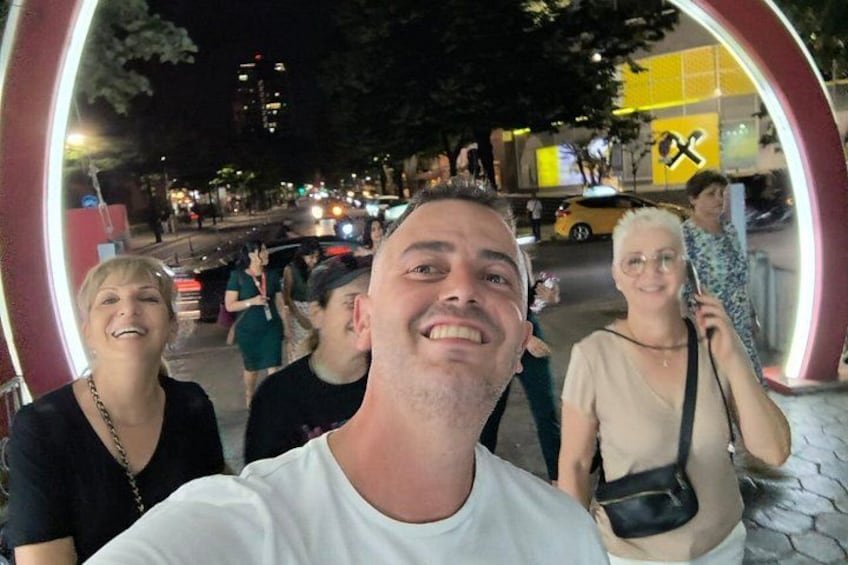 A group of people taking a selfie in an urban setting at night. 2