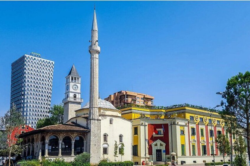 A mosque with a minaret, a clock tower, and a modern building with a checkered facade. 5