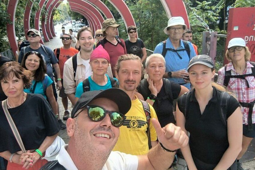 A group of people in an outdoor setting with a large circular structure in the background. 2