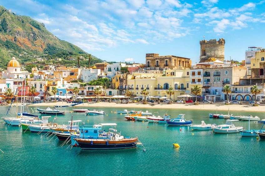 A coastal town with boats docked in the marina, historic buildings, and a prominent castle on a hill. 4
