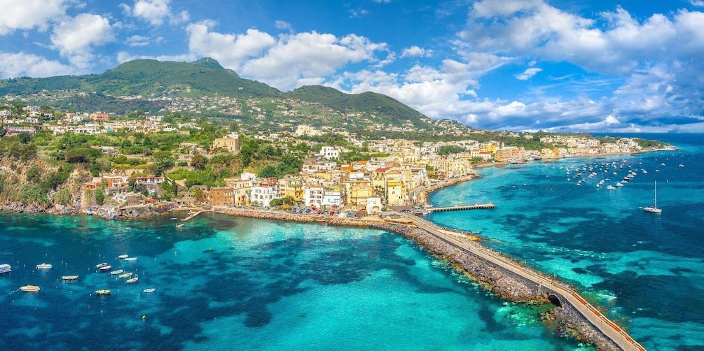 A coastal town with a clear blue sea, boats, and a mountainous backdrop. 5