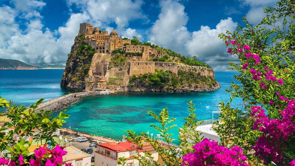 A coastal town with a historic castle on a cliff overlooking turquoise waters. 1