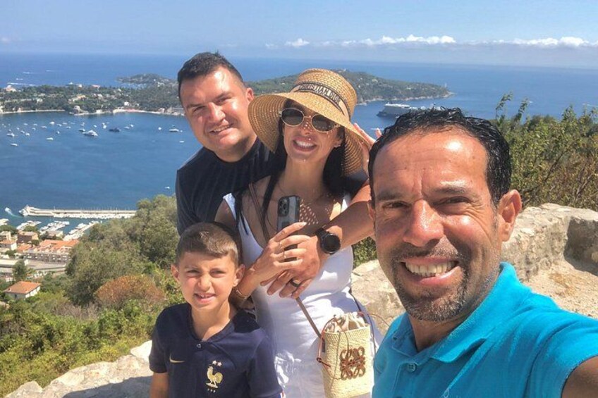 A family of four on a hill overlooking a coastal town with boats in the water. 1