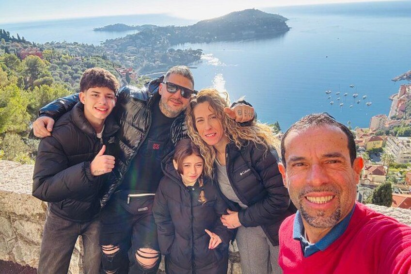 A group of people taking a selfie with a scenic coastal landscape in the background. 5