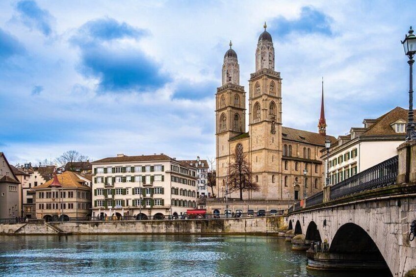 A river with a bridge, a cathedral with two towers, and surrounding buildings. 4