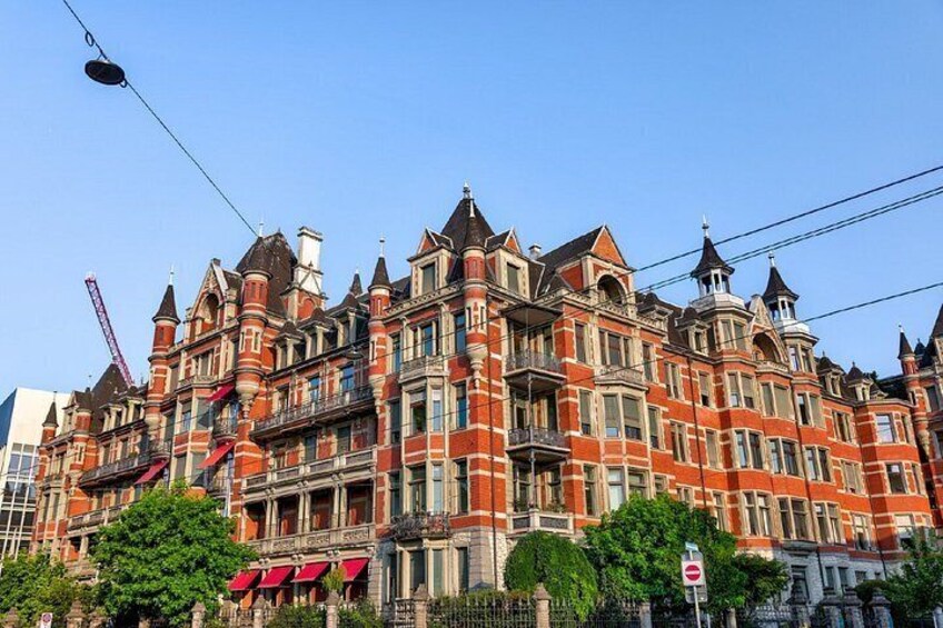A large, ornate building with multiple towers and balconies, surrounded by trees and a clear sky. 3
