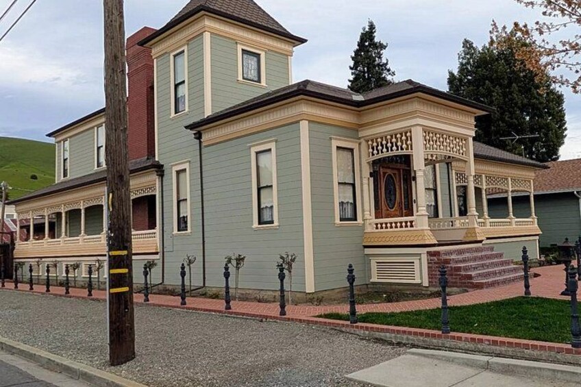 A two-story house with a porch, a small tower, and a well-maintained lawn. 3